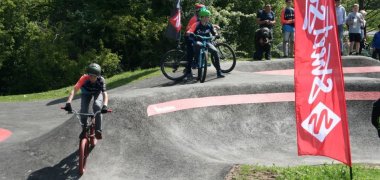 Kinder fahren mit ihren Fahrrädern auf dem Pumptrack