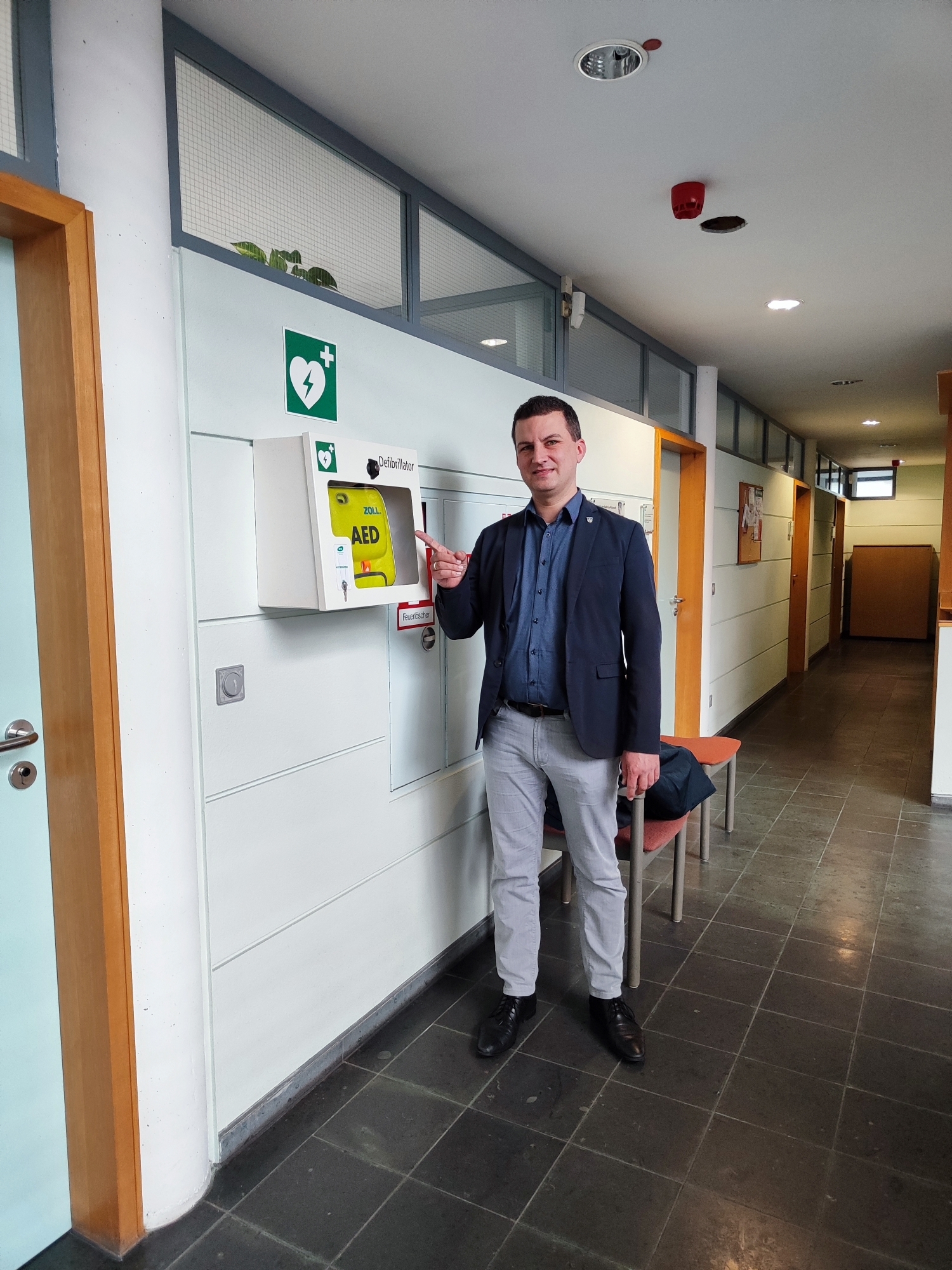 Bürgermeister Kirch vor Defibrillator im Rathaus