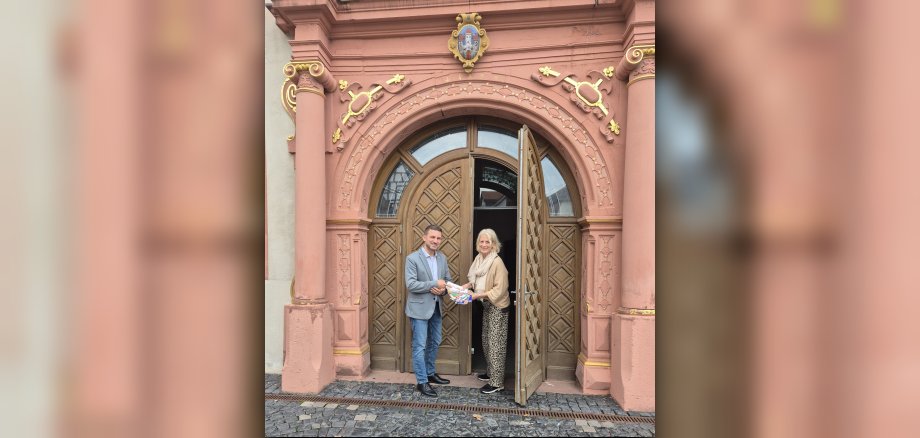 Kulturmanagerin Angelika Borchert übergibt Kulturprogramme an Bürgermeister René Kirch vor dem Kunstforum Säulenhalle