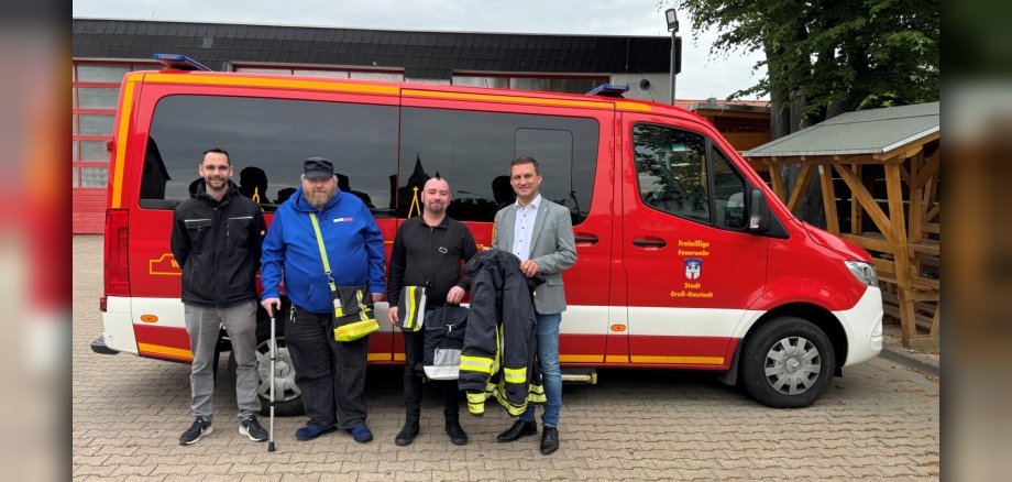 Foto: Bürgermeister René Kirch, Bastian Zellmann, Jörg Maul und Dennis Kotzian mit Upcycling-Produkten vor Feuerwehr-Fahrzeug