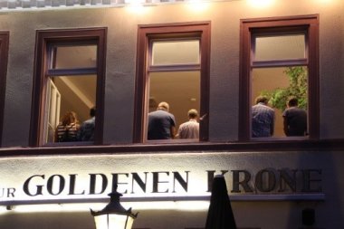 Blick von außen durch die Fenster auf Sängergruppe im Gasthaus Zur Goldenen Krone
