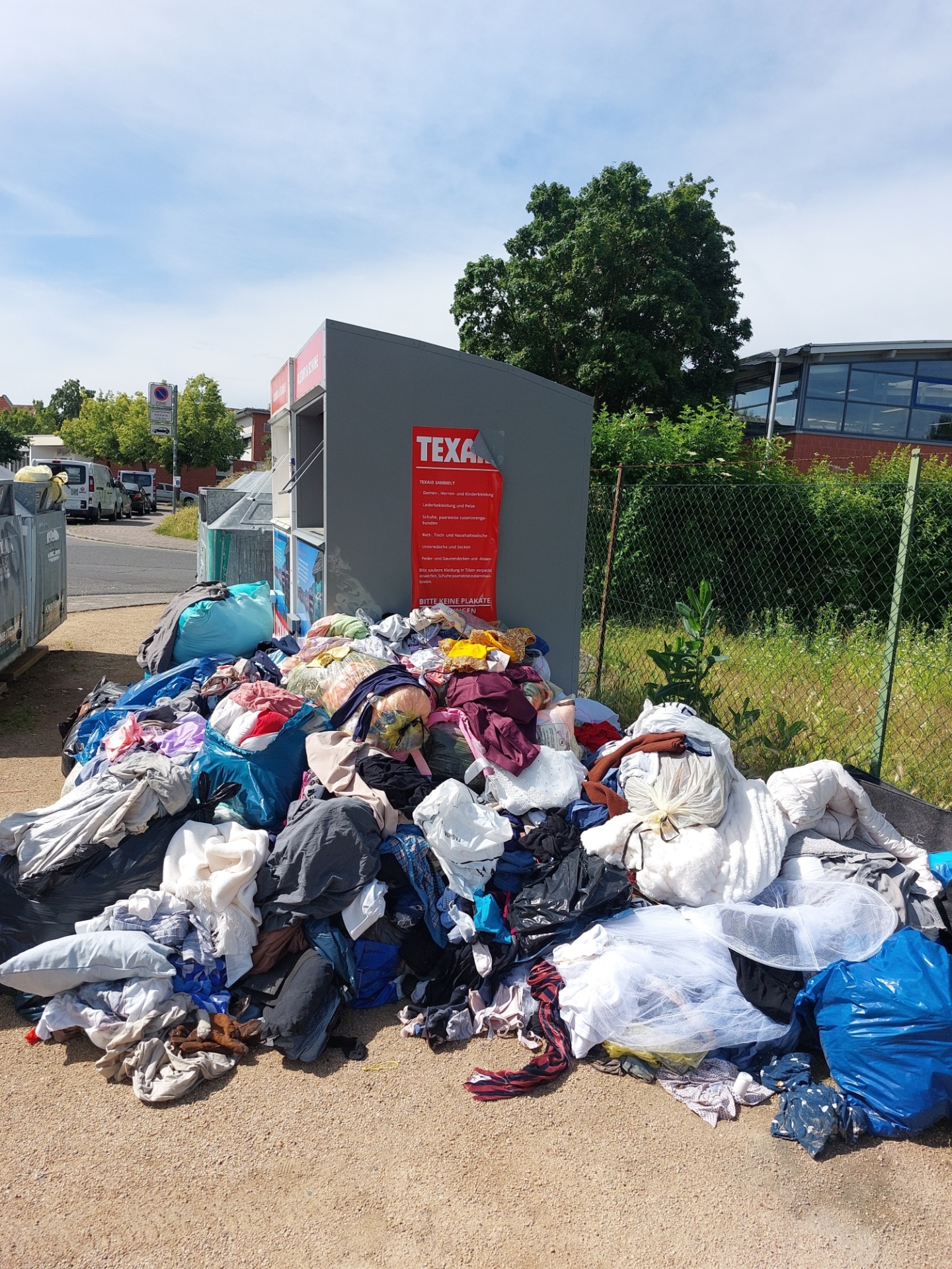 Altkleidersäcke vor Wertstoffcontainern liegend