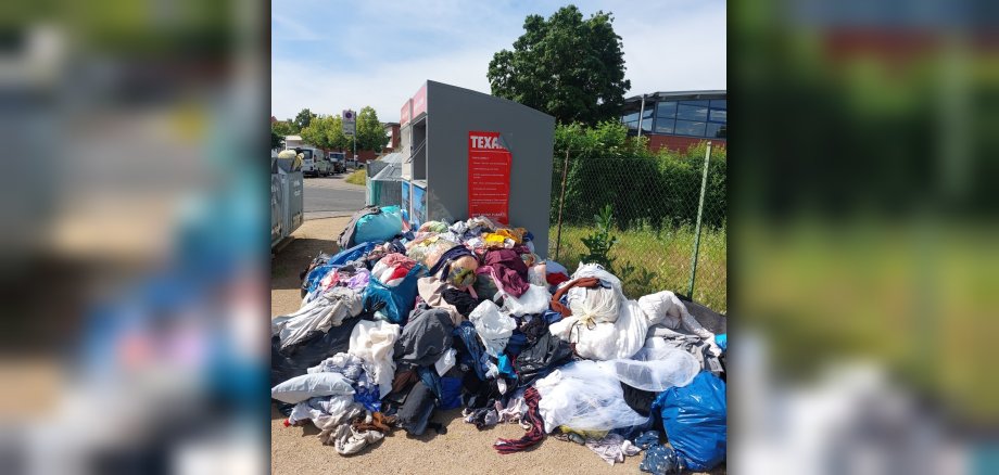 Altkleidersäcke vor Wertstoffcontainern liegend